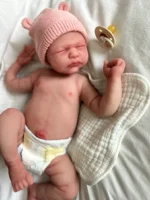 Handcrafted realistic newborn baby doll for collectors, featuring detailed hand-painted skin tones, soft touch body, and delicate eyelashes, posed on a cozy white blanket.