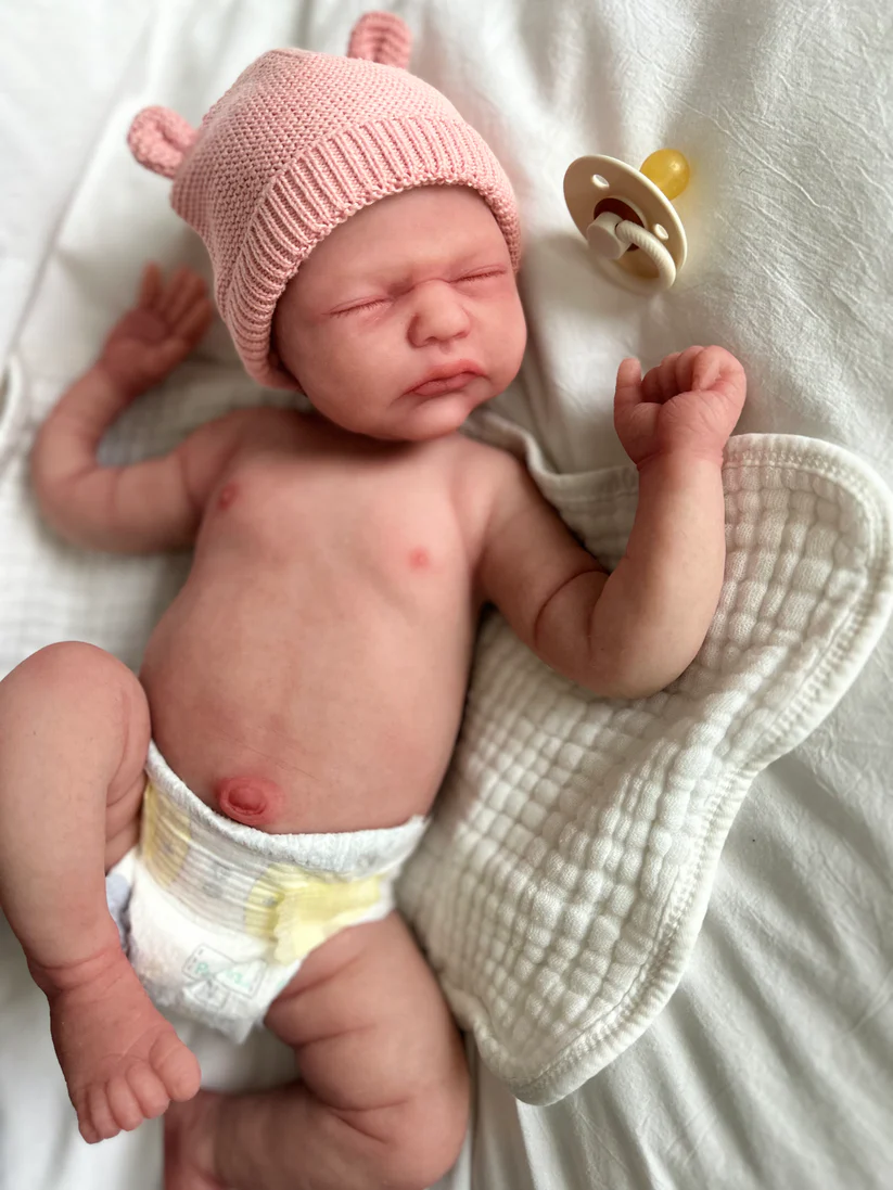 Handcrafted Realistic Newborn Doll for Collectors Handcrafted realistic newborn baby doll for collectors, featuring detailed hand-painted skin tones, soft touch body, and delicate eyelashes, posed on a cozy white blanket.