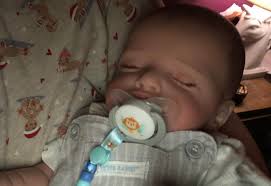 Lifelike reborn doll held gently by a caregiver in a memory care facility in the USA.